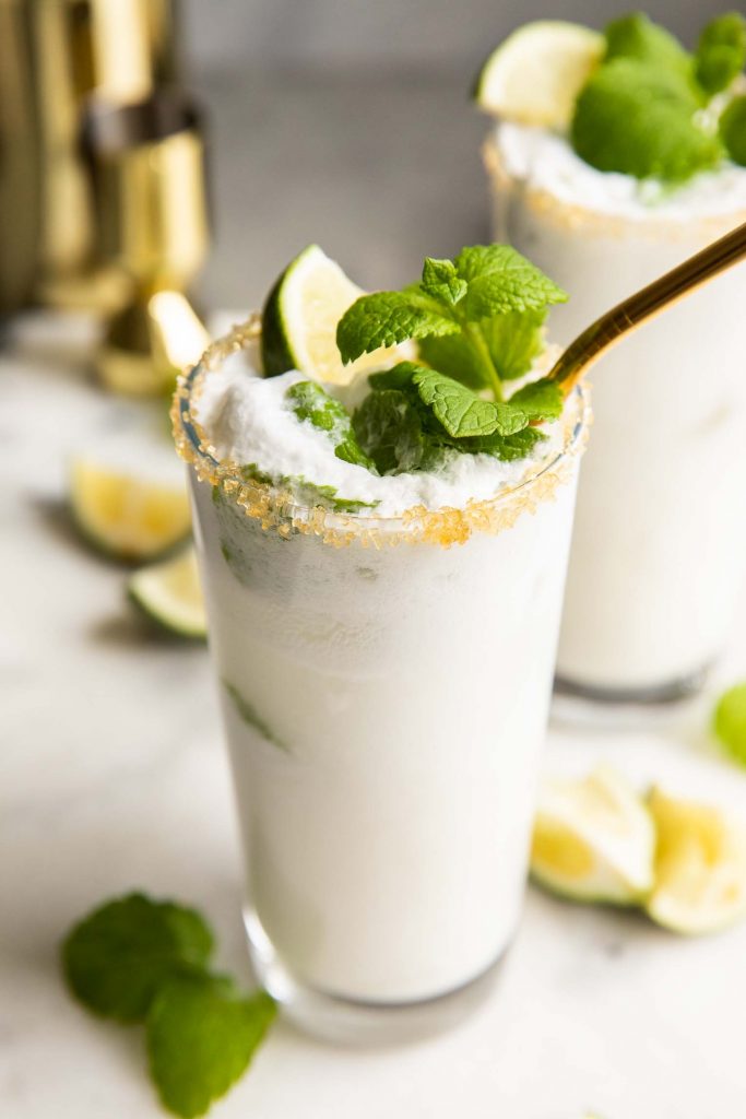 Across shot of a Creamy Coconut Mojito in a tall glass with cream on top.