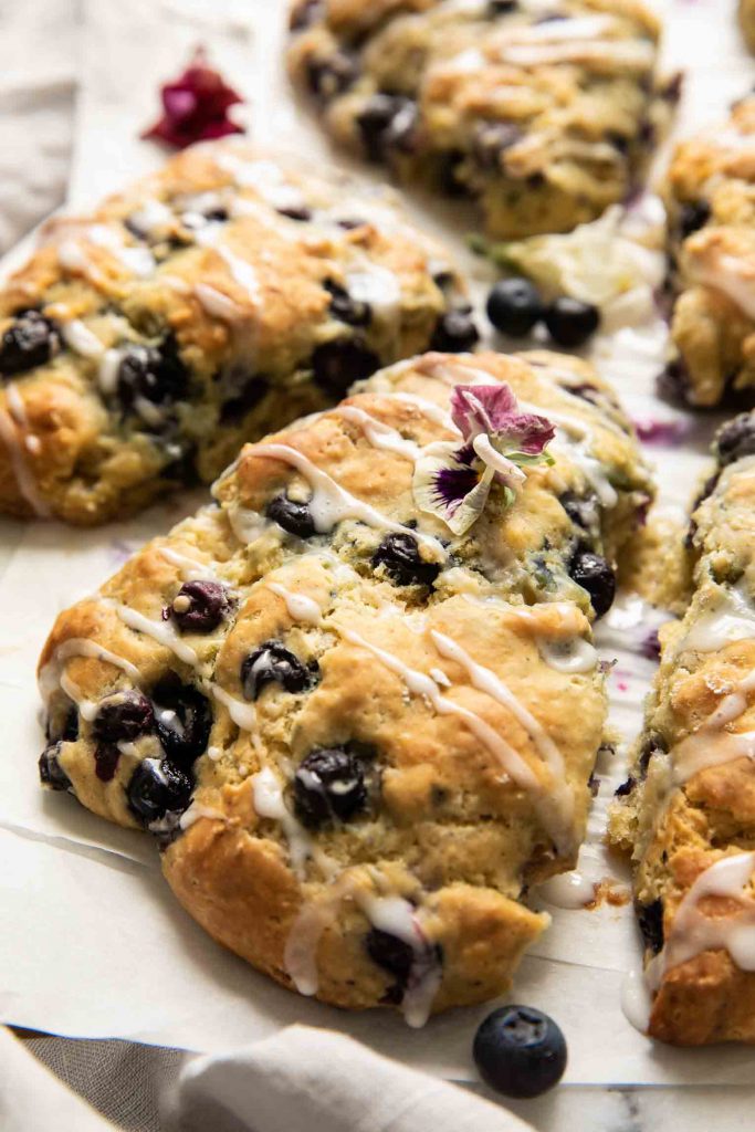 Angled shot of Maple Blueberry Scones on a baking sheet with parchment paper.