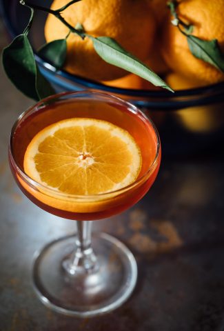 Orange cocktail in a glass with a slice of orange.