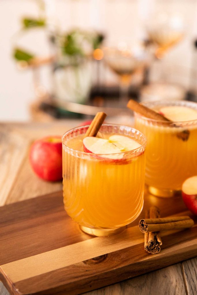 Apple Cider Bourbon Cocktail in glasses with cinnamon and apple slices.
