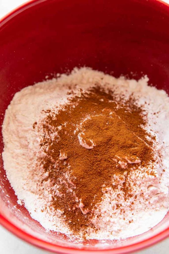 Dry ingredients for pudding cake in a red mixing bowl.