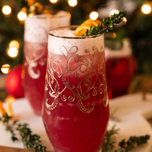 Spiced Cranberry Gin Fizz with rosemary and orange garnish.