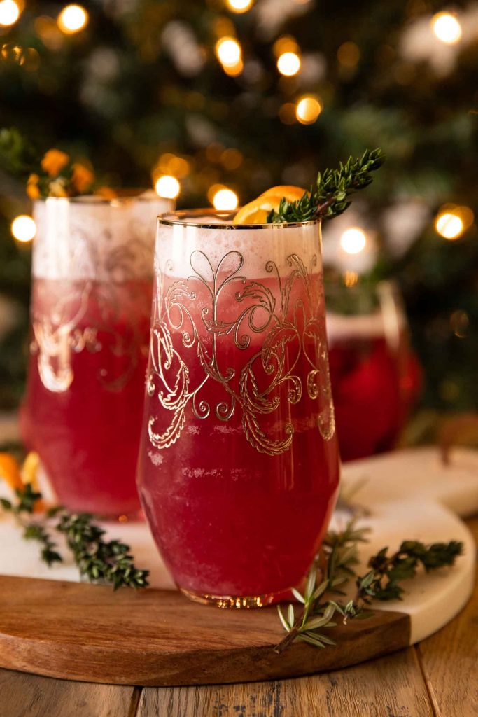 Spiced Cranberry Gin Fizz cocktails on a cutting board with Christmas tree.