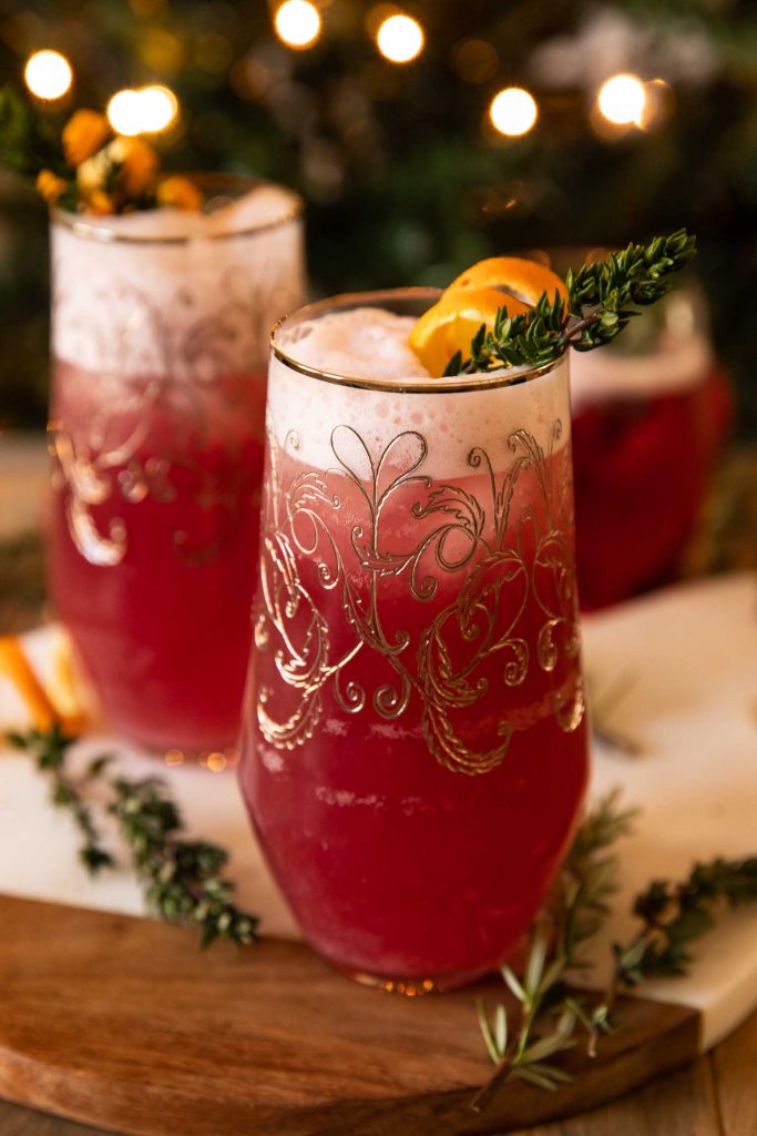 Spiced Cranberry Gin Fizz angled photo with holiday tree in background.