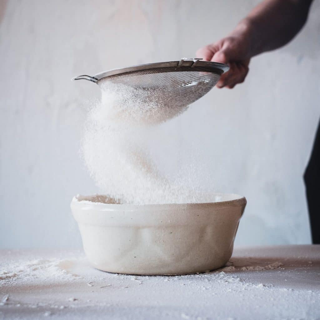 Powdered sugar being sifted into a container.