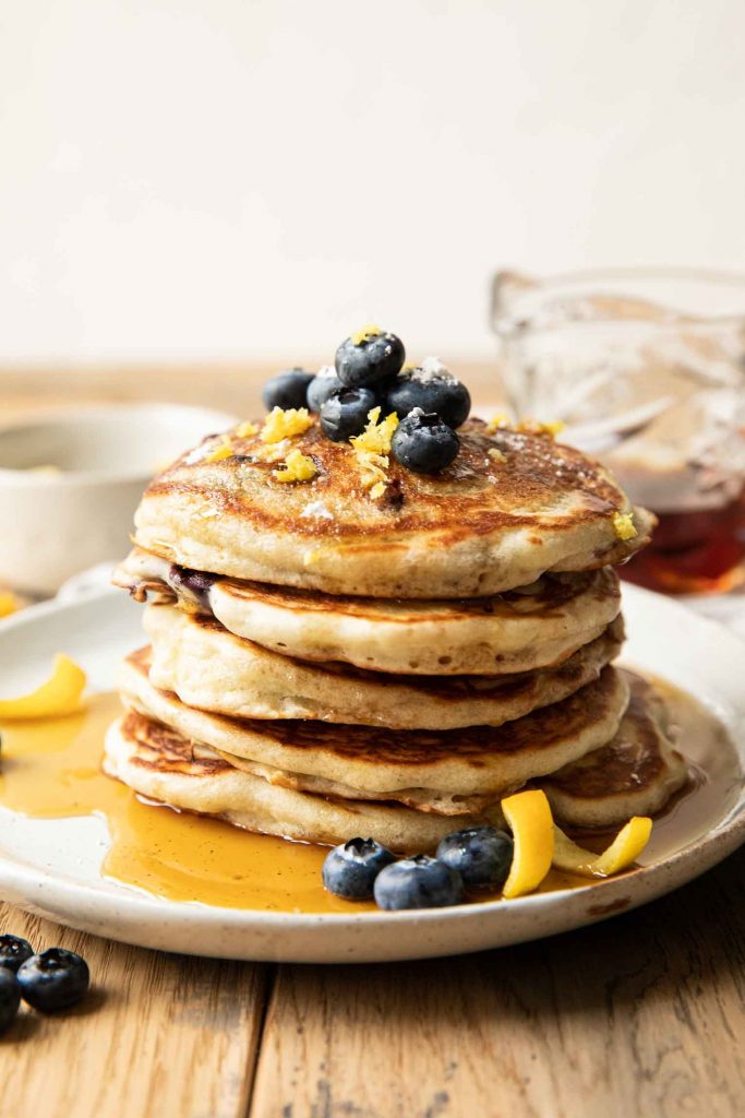 Lemon blueberry pancakes stack on a plate with syrup.