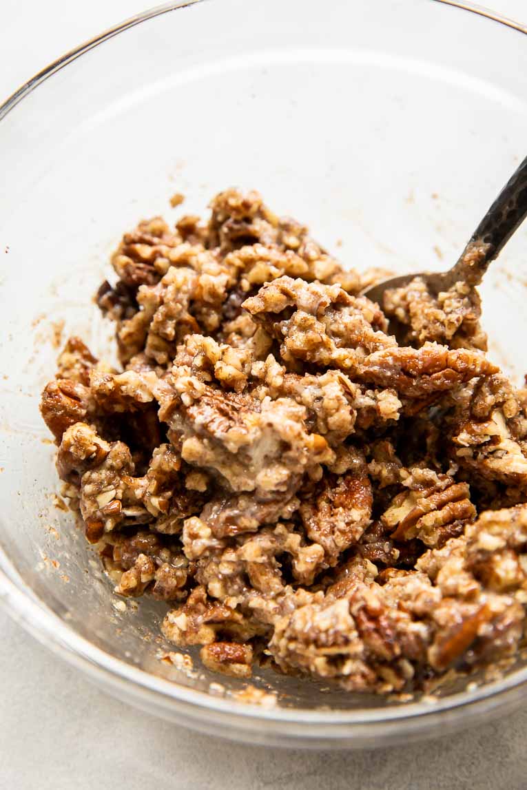Chopped pecans with butter and brown sugar in a mixing bowl.