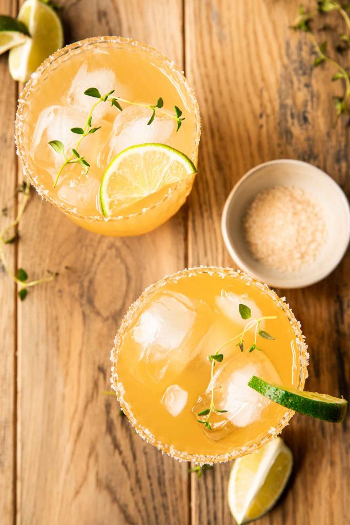 Top photo of two rum margaritas with a salt rim and lime.