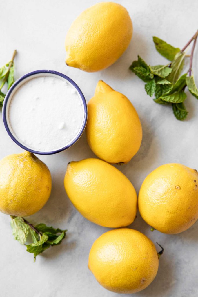 Lemons, sugar, and mint on a countertop.