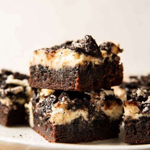 Oreo Cheesecake Brownies recipe stacked on a plate.