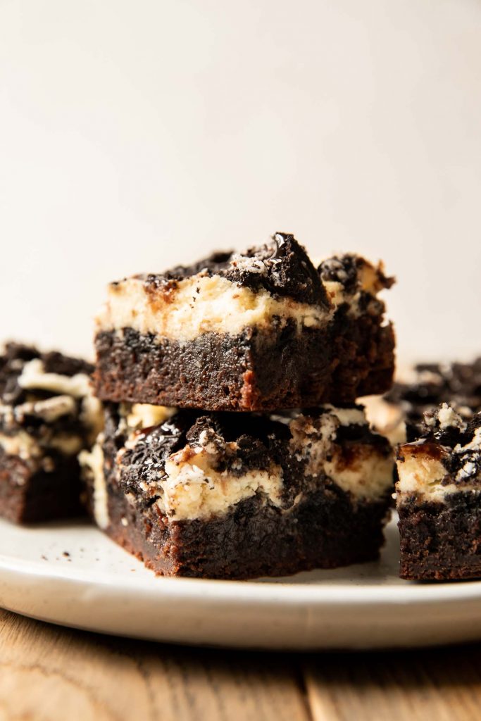 Oreo Cheesecake Brownies recipe stacked on a plate.