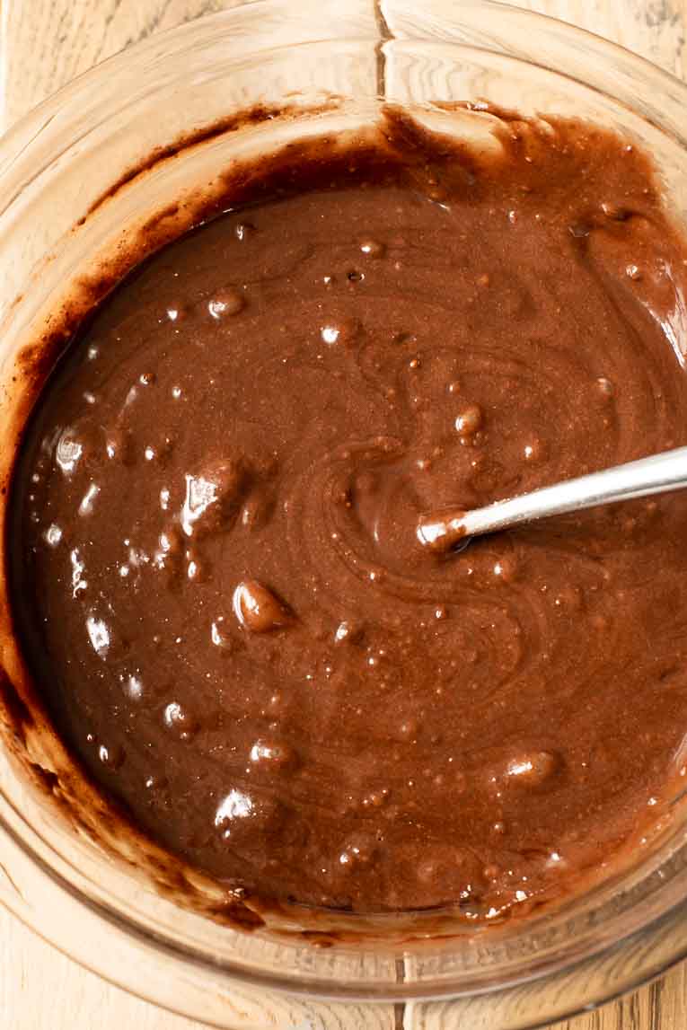 Brownie batter being mixed in a glass bowl.