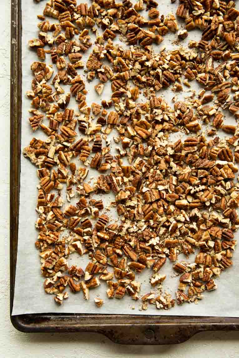 Pecans being toasted on a baking sheet.