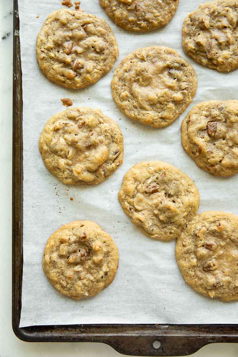 Coconut pecan cookies on a baking sheet with parchment paper.