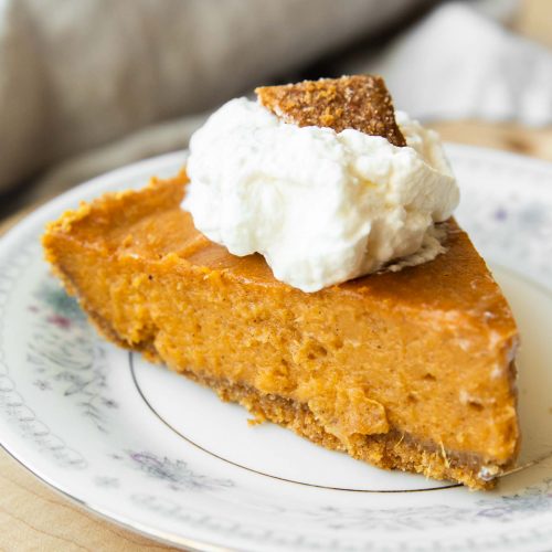 Slice of sweet potato pie with whipped cream and graham cracker.