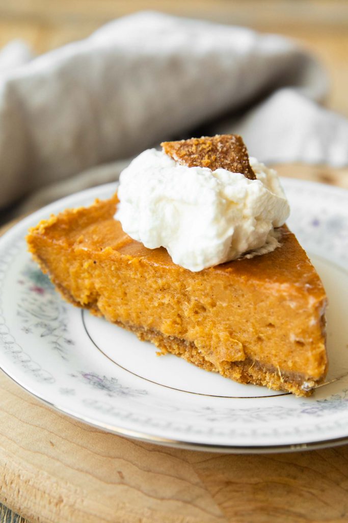 Slice of sweet potato pie with whipped cream and graham cracker.