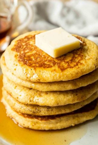 Angled close up of cornbread pancakes with butter.