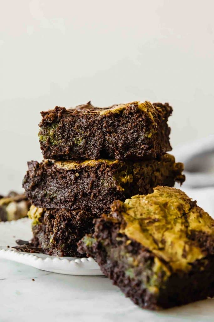 Stacked matcha green tea brownies on a plate.