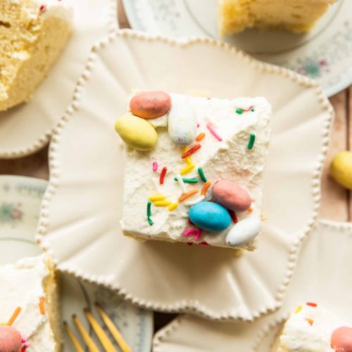 Easter Poke Cake slice with whipped cream icing, sprinkles, and robin eggs.
