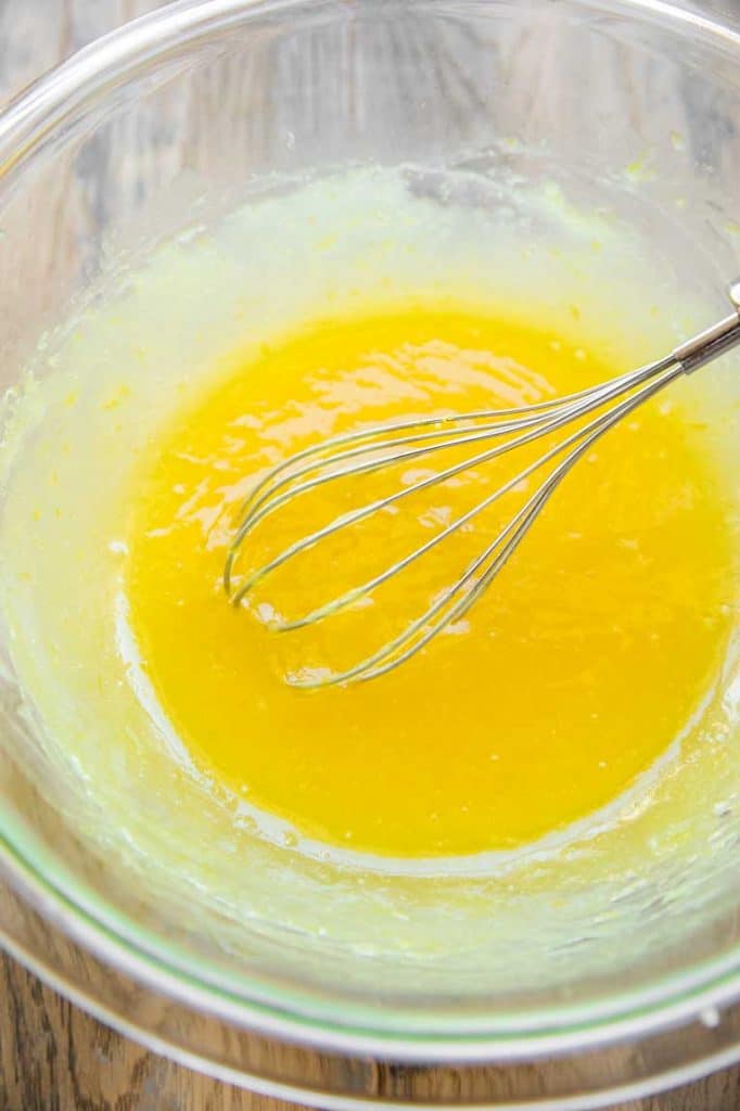 Lemon curd being whisked in a glass bowl.