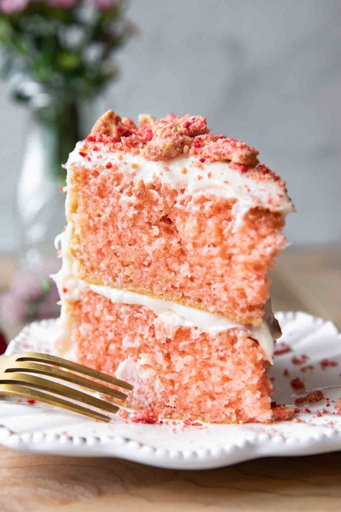 Close up of strawberry cake with buttercream icing and strawberry crunch on top.