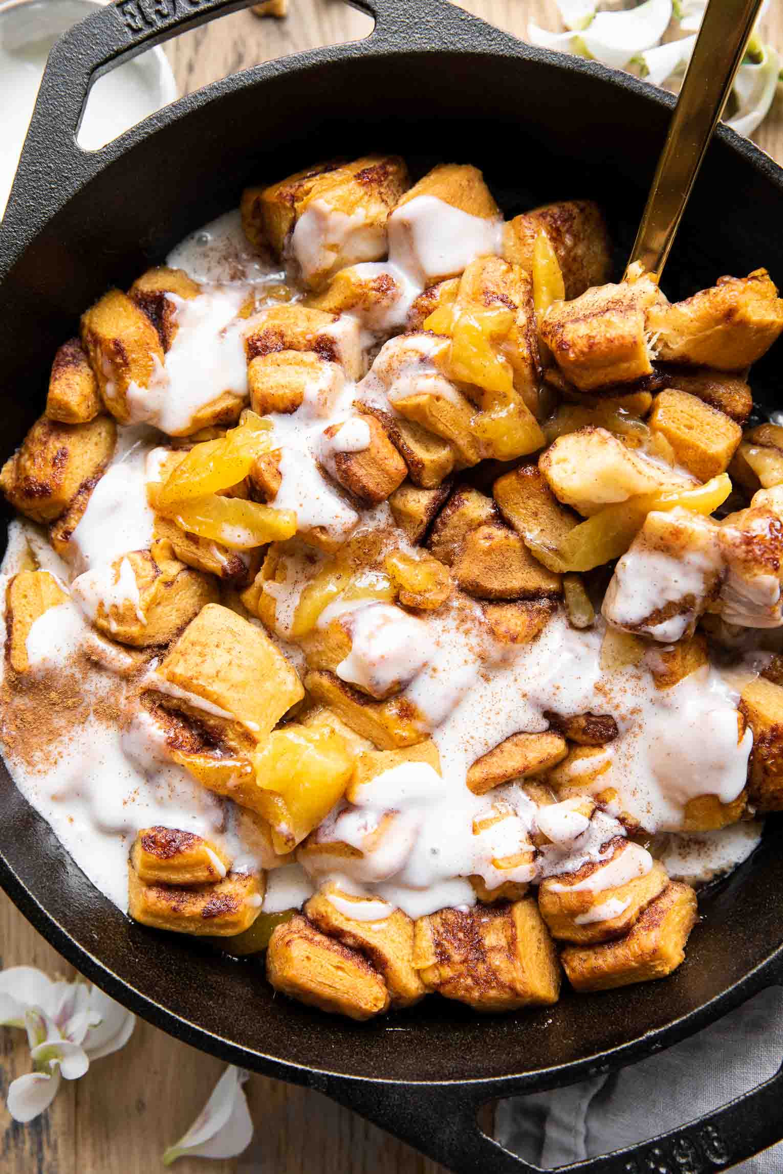Cinnamon Roll Peach Cobbler recipe in a skillet with icing.