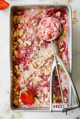 Strawberry Cheesecake Ice Cream in a pan with an ice cream scoop.