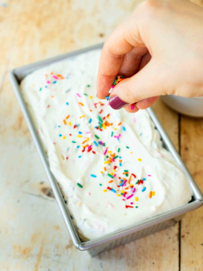 Ice cream batter with birthday cake and sprinkles in a loaf pan.