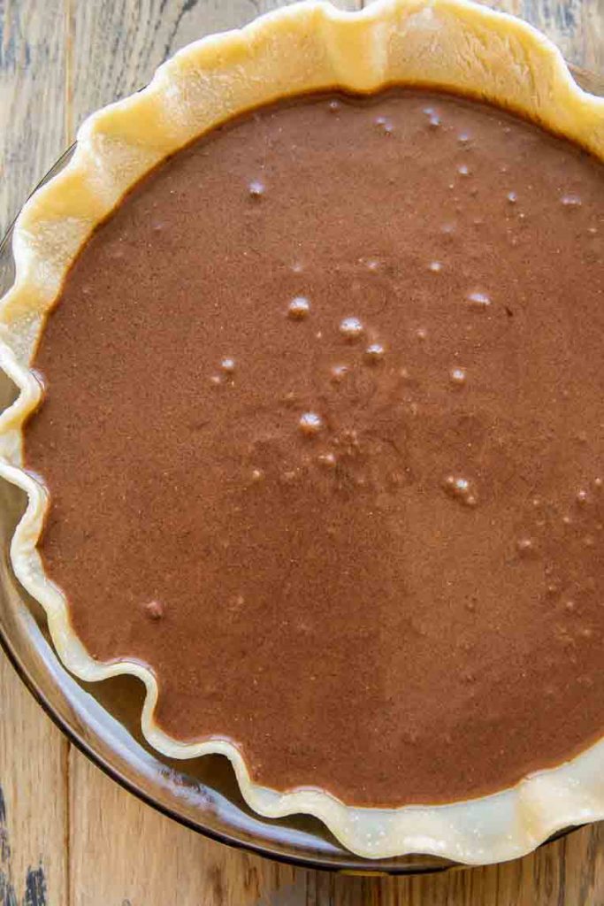 Chocolate chess pie filling poured into a pie crust.