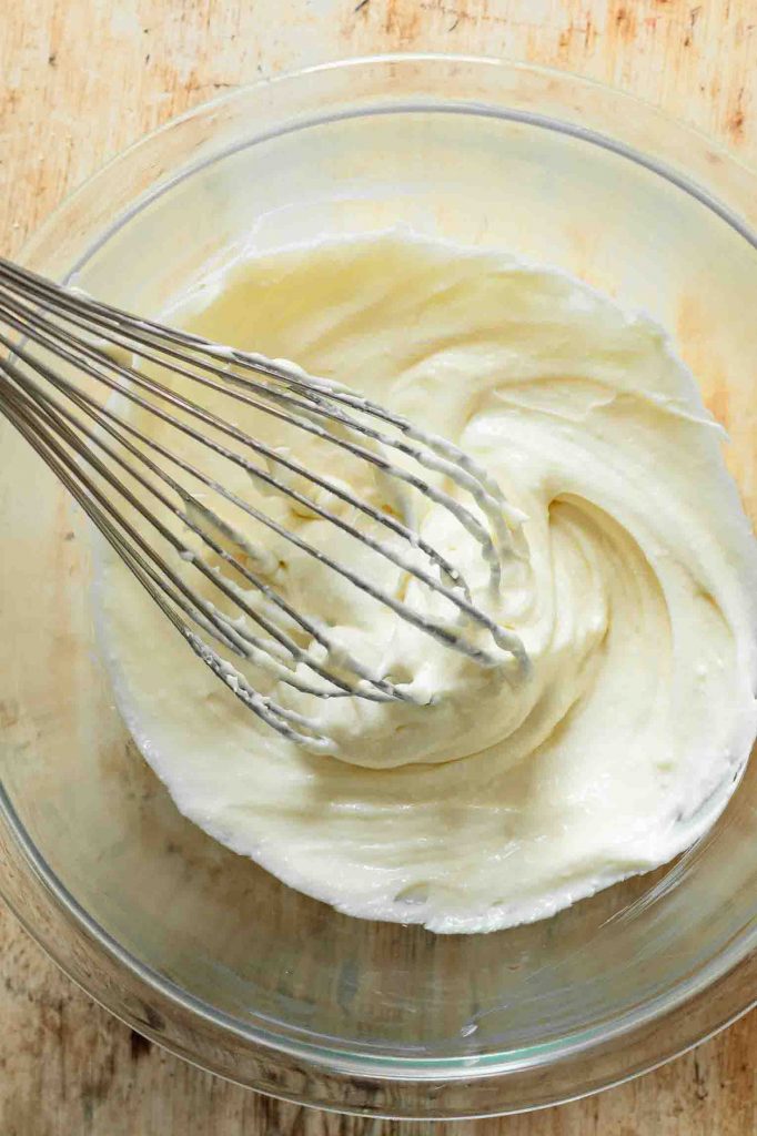 Cream cheese frosting being whisked in a bowl.