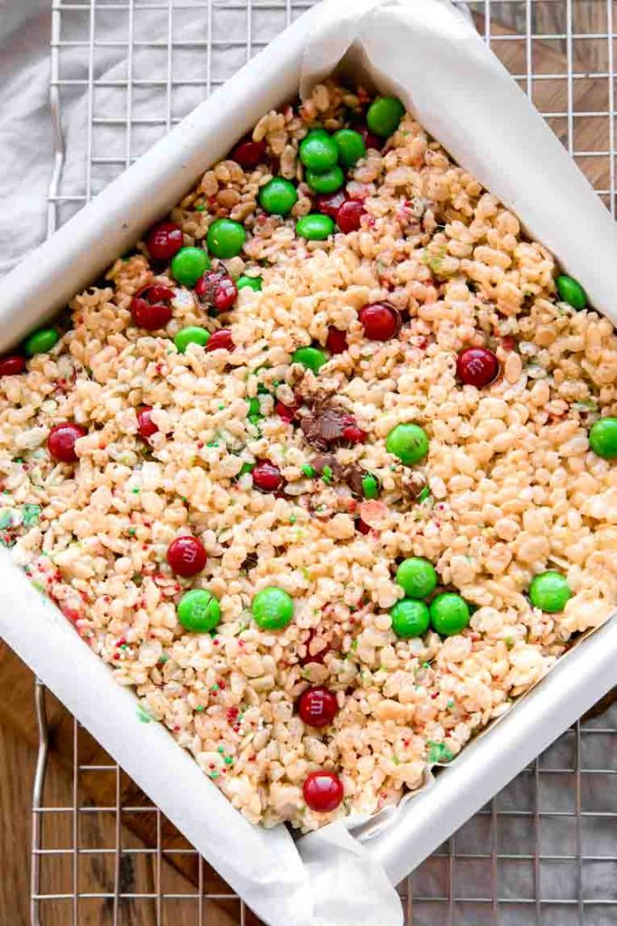 Rice Krispies treats in a baking pan with red and green sprinkles and M&Ms.