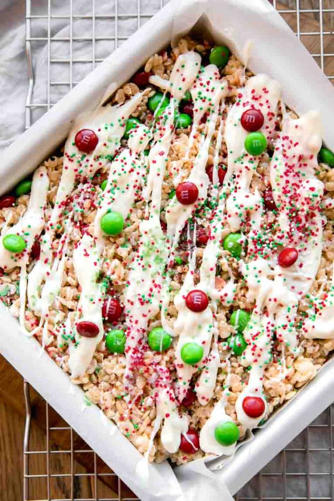 White chocolate and holiday toppings on rice krispies treats in baking pan.