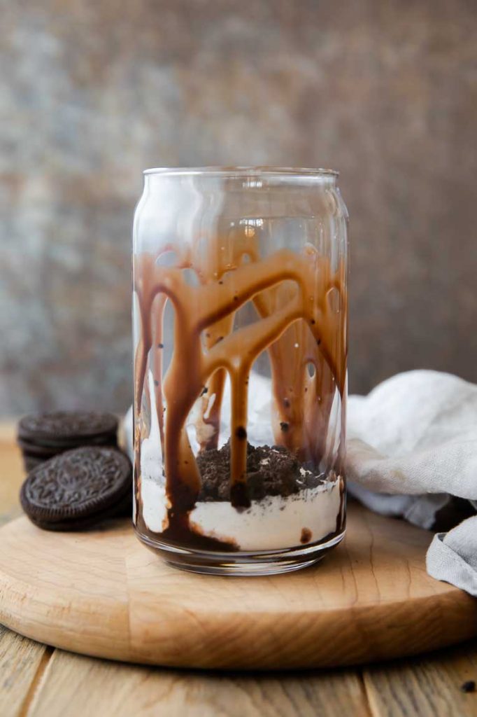 Chocolate sauce and whipped cream topped with cookie crumble on bottom of glass.