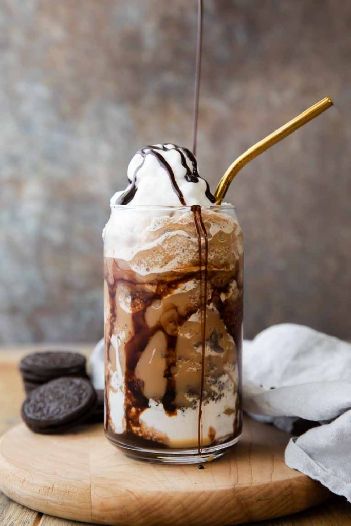 Mocha Cookie Crumble Frappuccino with whipped cream being drizzled with chocolate sauce.