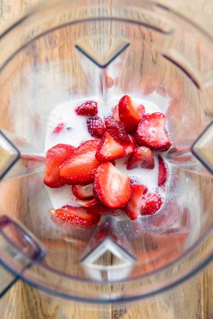 Strawberries, sugar, and milk in a blender.