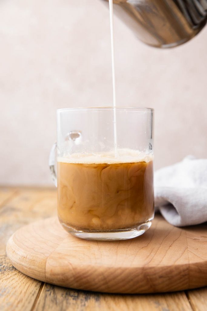 Steamed milk pouring into a chai tea espresso.