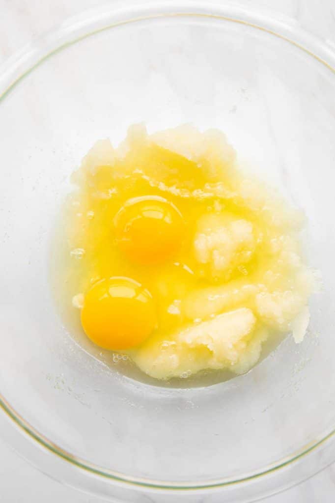 Eggs butter and sugar mixed together in a large mixing bowl.