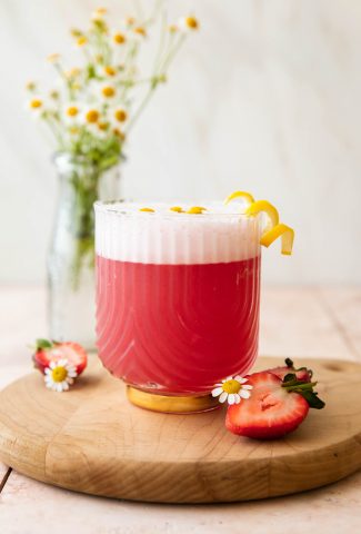Pink Gin Sour cocktail with flowers and strawberries.