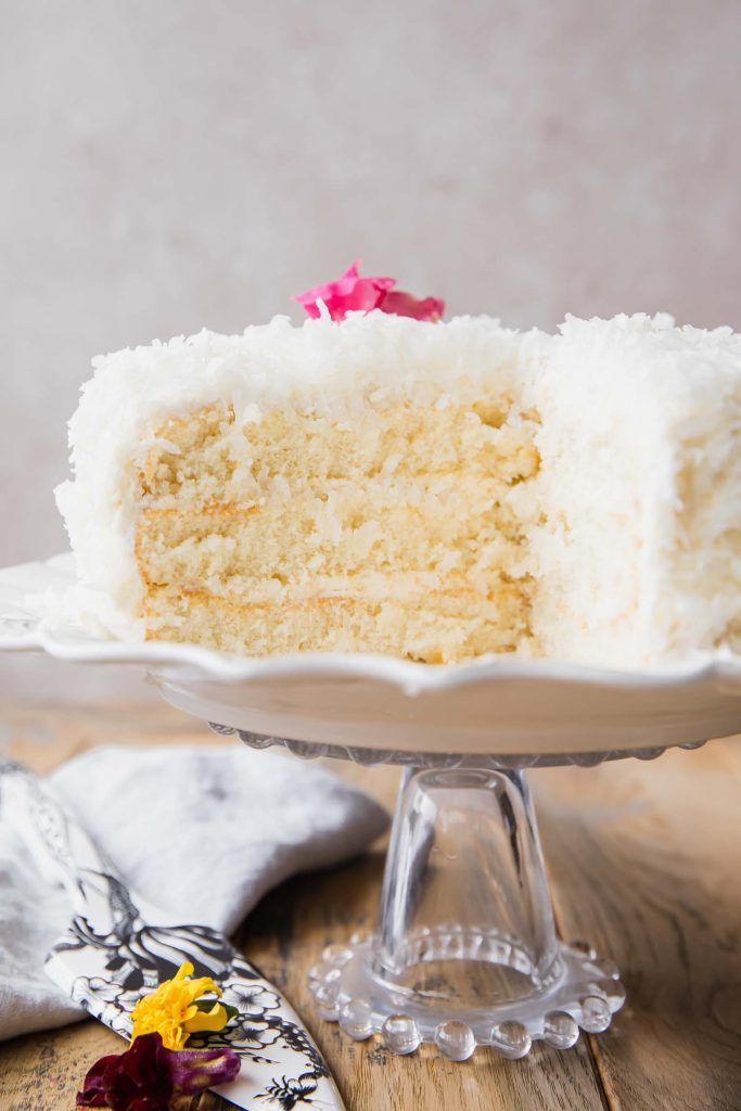 Coconut cake with a giant slice taken out to show layers.