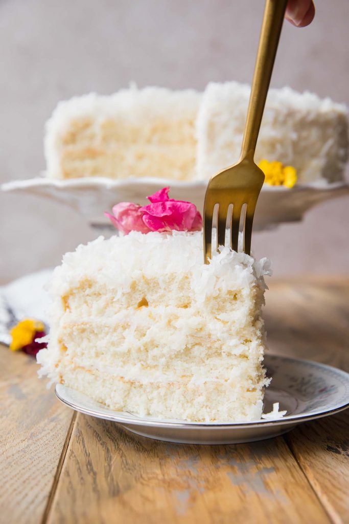 Coconut cake slice with a fork taking a bite.