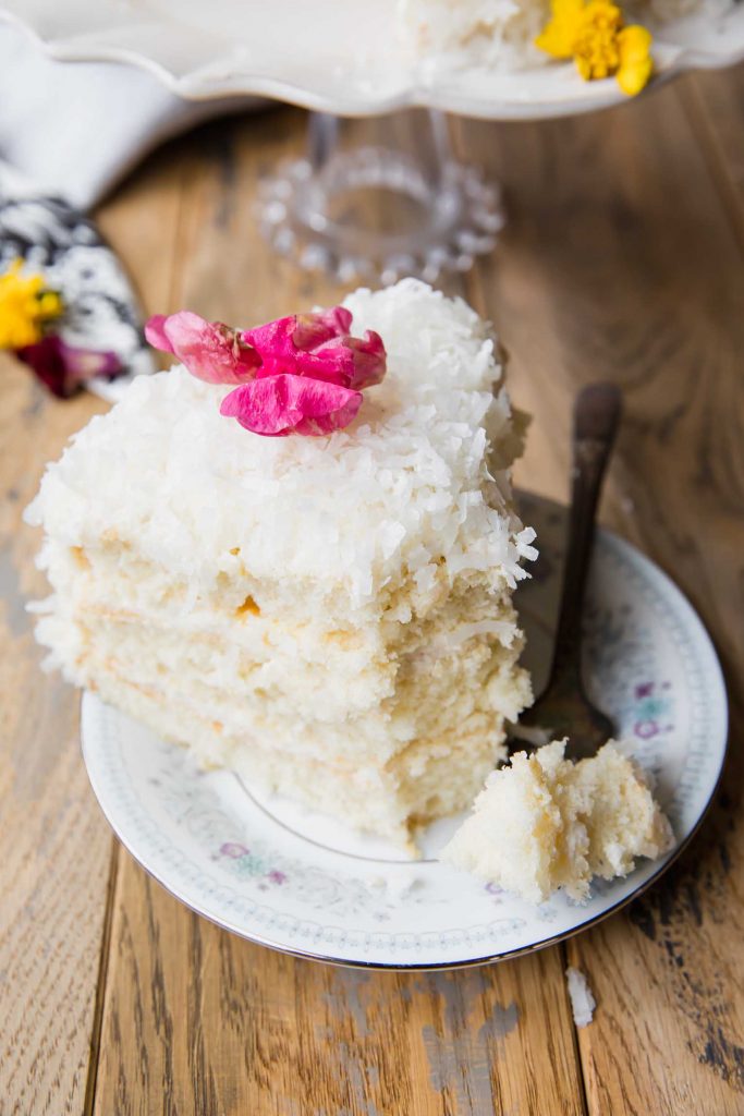 Coconut cake slice with a flower and bite taken out.