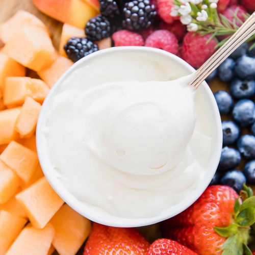 Close up of Cream Cheese Fruit Dip in a bowl with a spoon taking a bite.