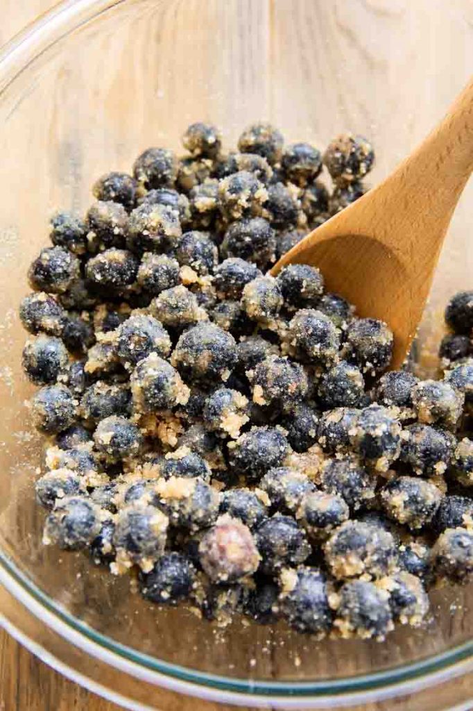 Blueberries with sugar and starch being mixed for filling.