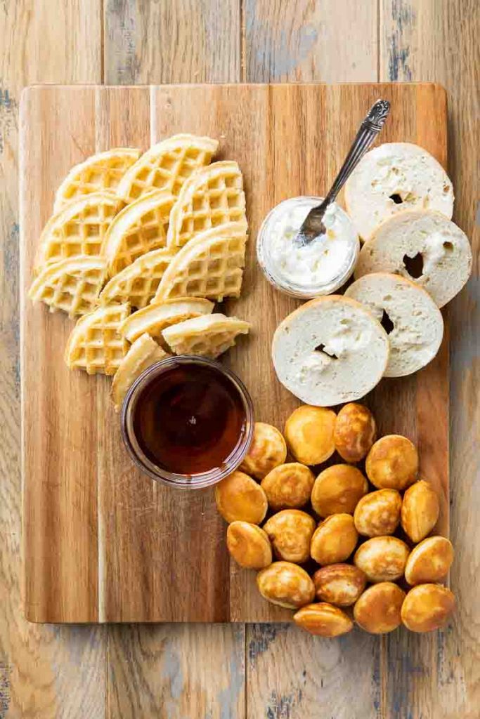 Waffles, pancakes, and bagels on charcuterie board.
