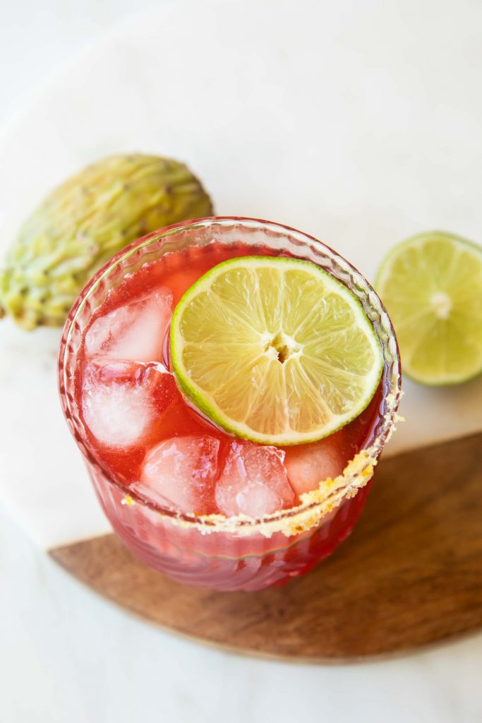 Top shot photo of glass with Prickly Pear Margarita and lime.