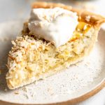 Coconut Custard Pie slice with whipped cream.