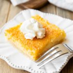 Angled photo of a Buttermilk Pie Bar with whipped cream.