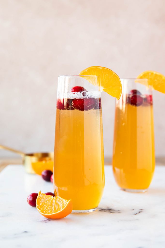 Easy Champagne Cocktail garnished with an orange slice and cranberries.