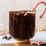 Peppermint Espresso Martini in a glass with peppermint rim and candy cane.