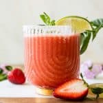 Across photo of Strawberry Margarita with lime wedge and sugar rim.